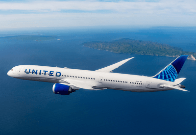 United airplane in the air, flying over water'